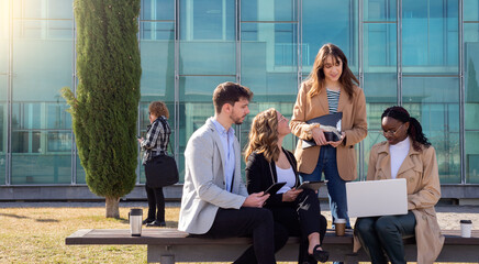 Business colleagues using laptop outside of office building