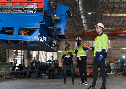 Caucasian Engineer man and team control and move big machine at metal factory 