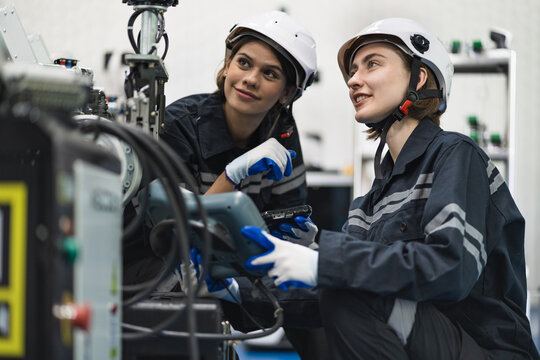 Two Engineer caucasian woman use remote control checking arm robot in the machine lap	