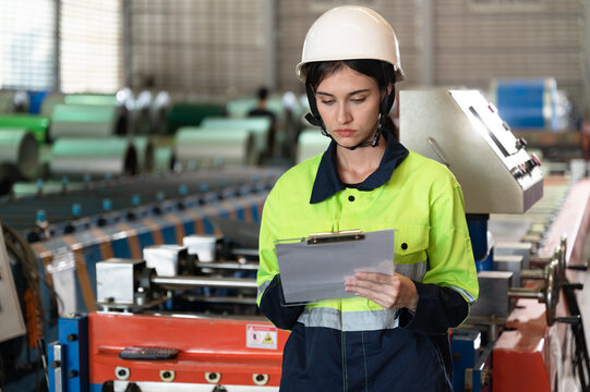 Portrait engineer woman use clipboard working with machine at metal sheet factory	