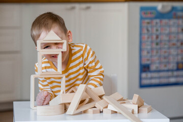 A little boy of 3 years old is playing a developing logistics constructor. Children's wooden toys....