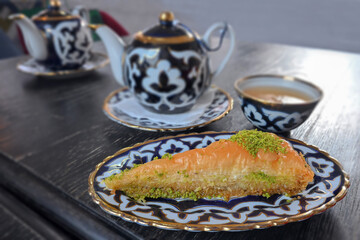 A cup of green tea with pastries.
Tea party in Uzbek style. Green tea and Turkish baklava.  Uzbek cuisine. National cuisine.