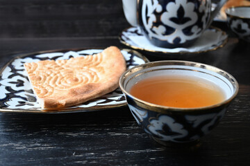 A cup of green tea with pastries.
Tortillas and green tea in a bowl. Tea party in Uzbek style. Uzbek cuisine. National cuisine.