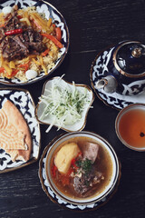 Lunch in ethnic, national, Uzbek style. Uzbek lunch with shurpa, pilaf, green tea in a teapot.