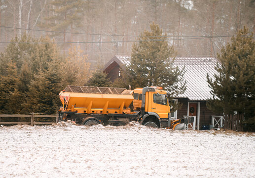 Salt spreader or salt truck cleaning the road in the countryside after heavy snowfall. Gritter cleaning driveway.