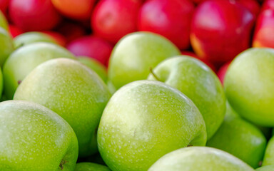 Fresh red and green apples spread on the counter for sale, create a natural, colorful background.