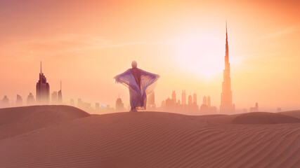 Woman in traditional arab dress stands on the mountains and rises her hand. Dubai city silhouette...