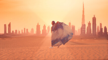 Woman in traditional arab dress stands on the mountains and rises her hand. Dubai city silhouette on the background