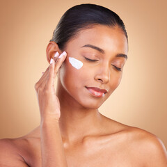 Beauty, skincare and face of Indian woman with cream in studio for wellness, glowing and spa...