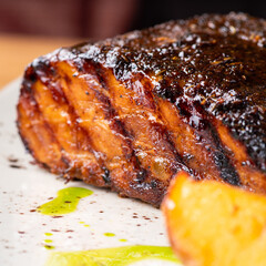 Close up Gourmet Main Dish with Grilled Pork Rib and Fried Potatoes on White Plate. S
