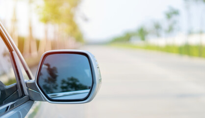 Rear view of a silver SUV car driving on a forest road. Green forest blurred  and big road in the background.