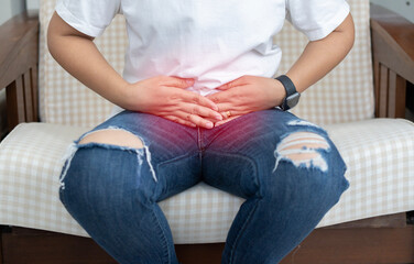 Fototapeta premium Young beautiful woman having painful stomachache and sitting on sofa at home. Chronic gastritis.