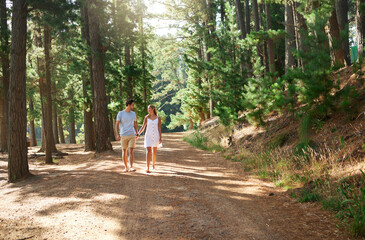 Fototapeta na wymiar Walking, happy and a couple holding hands in nature for love, a date or holiday in Switzerland. Smile, care and a young man and woman on a walk in a forest, woods or mountains during a vacation