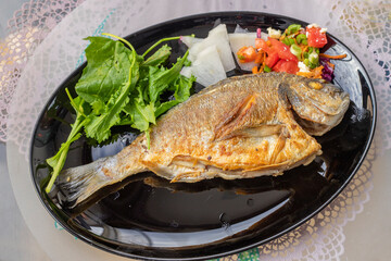 Fried sea bream in a black plate