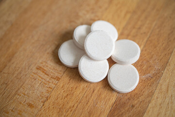 Fototapeta na wymiar large, round white tablets lie on a wooden table surface. Flu and cold season, new virus strain. Lack of vitamins in autumn, spring and winter, uncontrolled medication