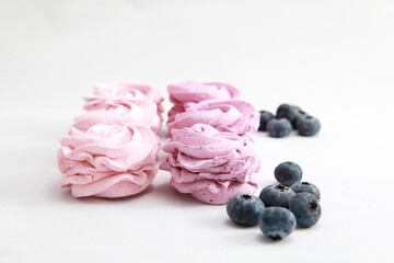 Close-up of natural pink berry marshmallow on a white background with blueberries