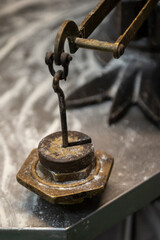 Detalle de una antigua bascula de metal con peso en plomo