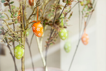 Easter eggs on a tree with green leaves on the branches.   