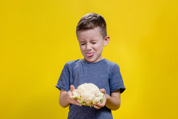 A charming little boy refusing to eat cauliflower. Healthy food