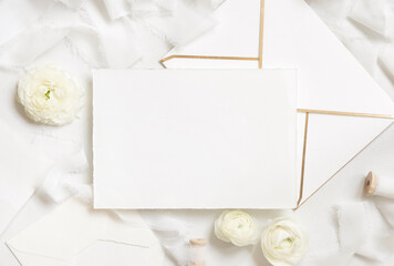 Blank card and envelope near cream roses and white silk ribbons top view, wedding mockup