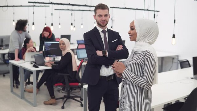 International multicultural team at work: in coworking office, afroamerican muslim woman with hijab and caucasian manager man
