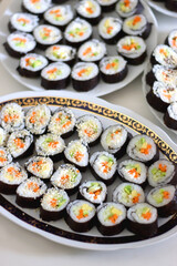 Plates with homemade sushi rolls on white table. Tuna and vegetable sushi, and vegetarian cream cheese and vegetable sushi. Selective focus.