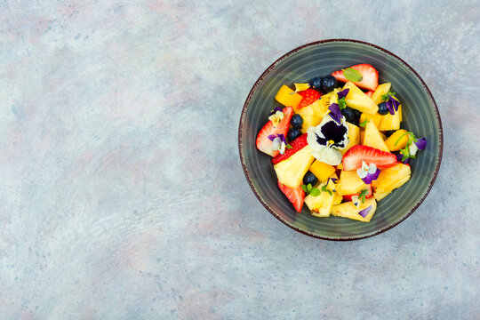 Bright fruit salad with edible flowers.