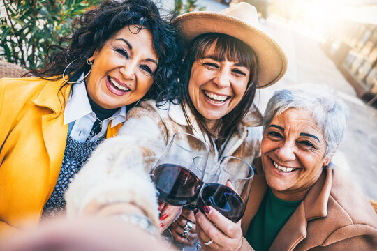 Happy mature women taking selfie pic with wine glasses outdoors at city urban street- Group of three senior friends having fun together on holiday- Elderly Joyful Lifestyle Concept 