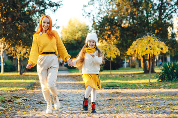Fototapeta premium Family enjoying the beautiful autumn nature. Mom and child having fun together. Autumn fashion, lifestyle.