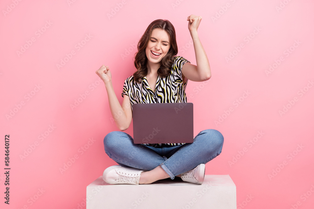 Wall mural Full body photo of delighted positive lady sit podium use netbook raise fists achievement luck isolated on pink color background