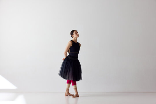 Beautiful ballerina, female ballet dancer wearing black dress dancing isolated over white background. Beauty and grace