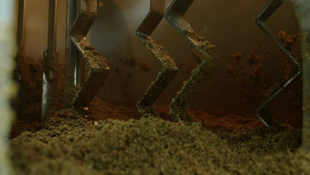 Close-up shot of mass of spent grain lying inside lauter tun with zigzag shaped blades at craft brewery