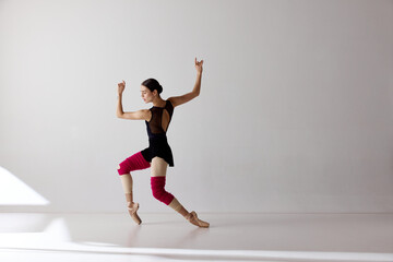 One young ballerina wearing pointe shoes dancing on fingertips over white background © Lustre Art Group 