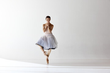 Charming ballerina posing with folded hands smiling with closed eyes over white background © Lustre Art Group 