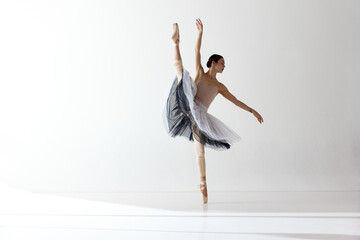 Young and incredibly beautiful ballerina is posing and dancing in a white studio. Classical ballet...