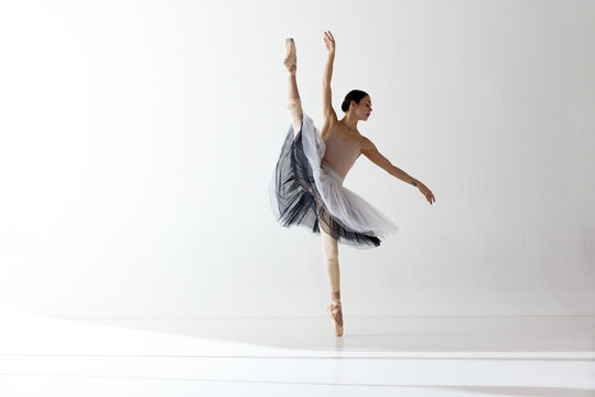 Young and incredibly beautiful ballerina is posing and dancing in a white studio. Classical ballet art