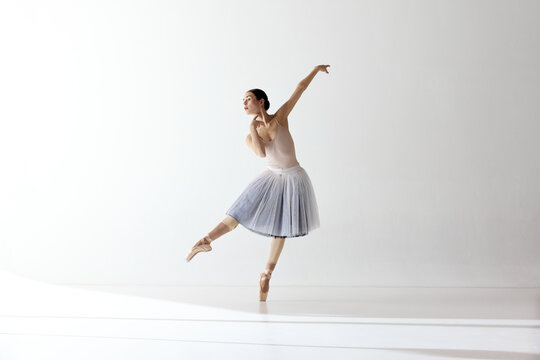 Beautiful woman ballet dancer dancing over white background. Art, theater, skills, aspiration concept