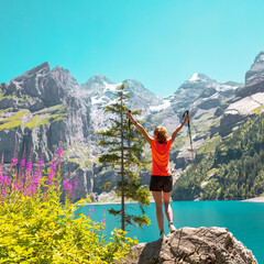 Happy hiker woman standing on rock looking at majestic view of mountain and lake- Switzerland