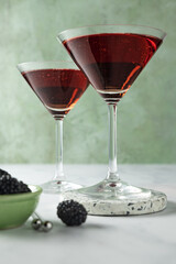 Two blackberry cocktails against a green background