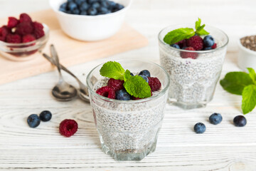 Healthy breakfast or morning with chia seeds vanilla pudding raspberry and blueberry berries on table background, vegetarian food, diet and health concept. Chia pudding with raspberry and blueberry