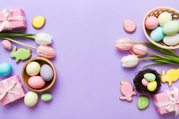 Easter frame with eggs, gift box and tulip on a colored background. The minimal concept. Top view Happy Easter composition. Card with a copy space of the place for the text