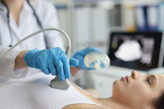 Female doctor examines woman breasts using ultrasound machine