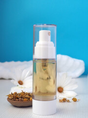 Dried chamomile flowers and a bottle of natural tonic for face and body