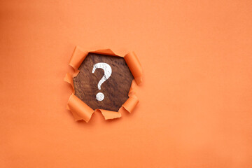 A question mark sign on the wooden table with torn paper effect