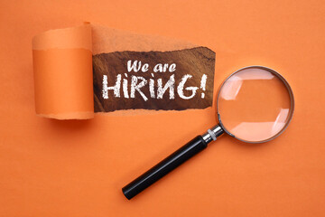 WE ARE HIRING text is written on the wooden background with torn paper effect. Top view, flat lay