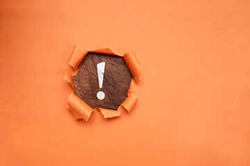 An exclamation mark on the wooden background with torn paper effect. Top view, flat lay