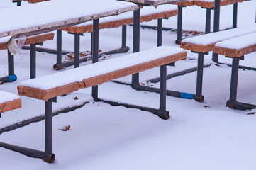 Tables and benches in a street cafe are covered with snow in winter. No people. Harsh continental...