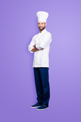 Full size body portrait of joyful positive chef cook with stubble in beret, having his arms crossed, isolated over grey background, looking at camera