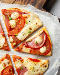 Close-up, pieces of Italian pizza on a wooden board. Top view pizza with mozzarella cheese, pepperoni, tomatoes and spices.