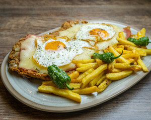 Milanesa de carne de ternera con topping de jamon queso y huevos acompaña de papa fritas